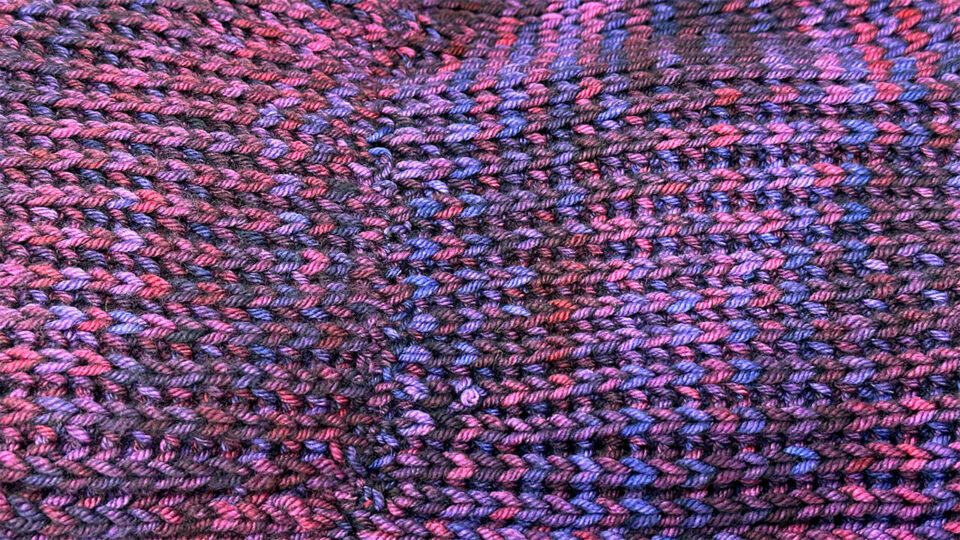 A photo of a a hand knitted brioche infinity scarf closeup, showing messy seaming.
