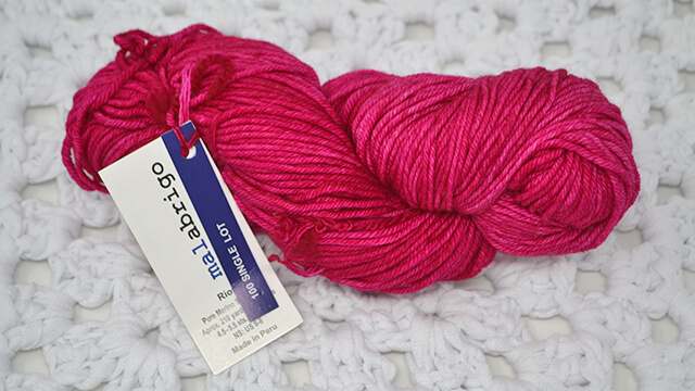 A photo of a skein of Malabrigo Rios Hot Pink yarn,
